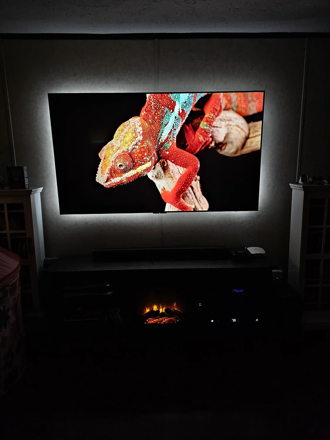 A wall-mounted TV with a colorful chameleon image, bias lighting and a soundbar