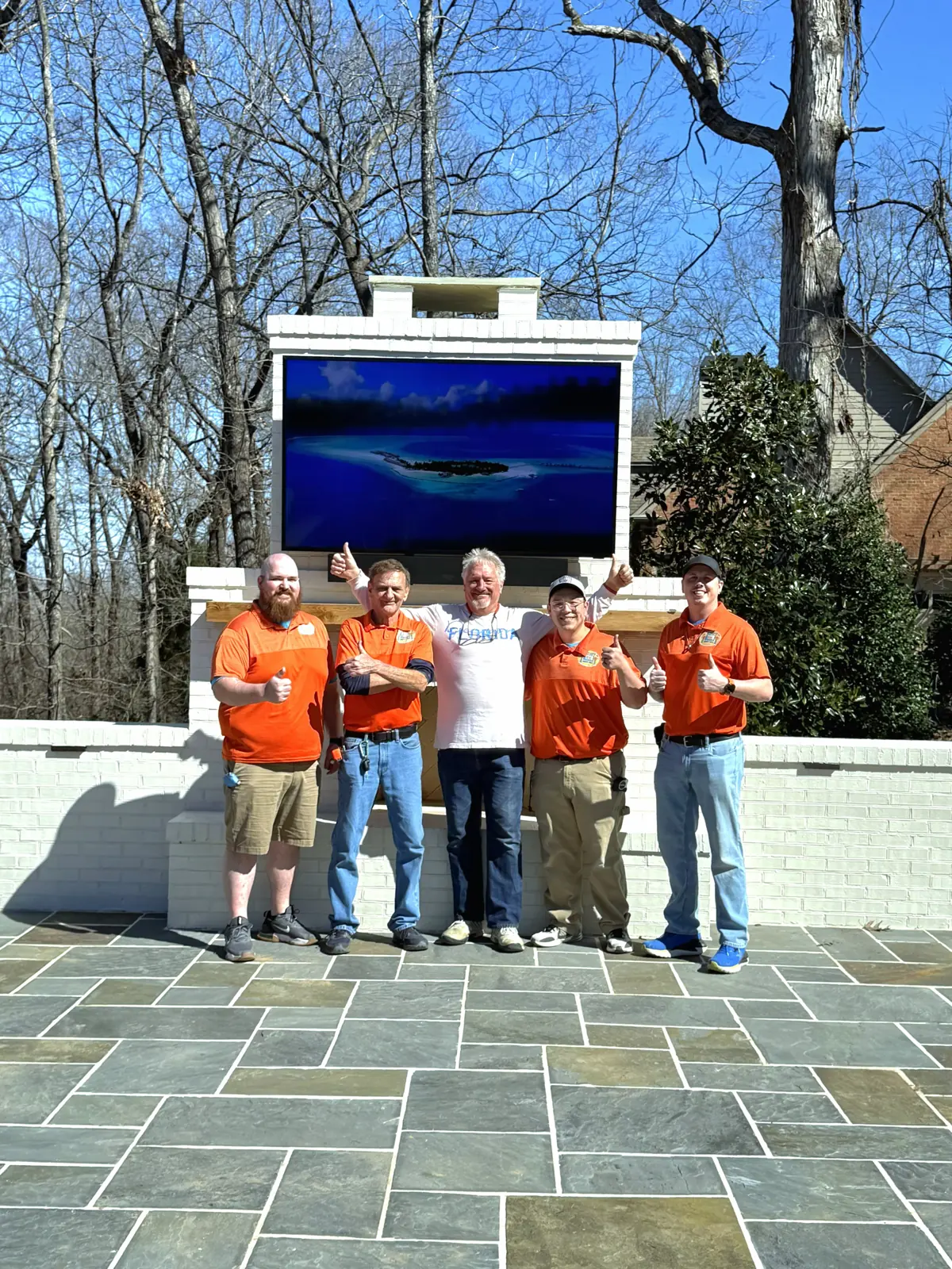 Five people gathered beside a completed outdoor TV installation